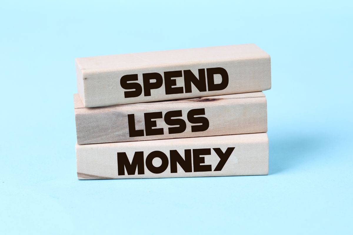 The photo of wooden rectangles with words referring to live below your means allows more money to go toward investments and savings.