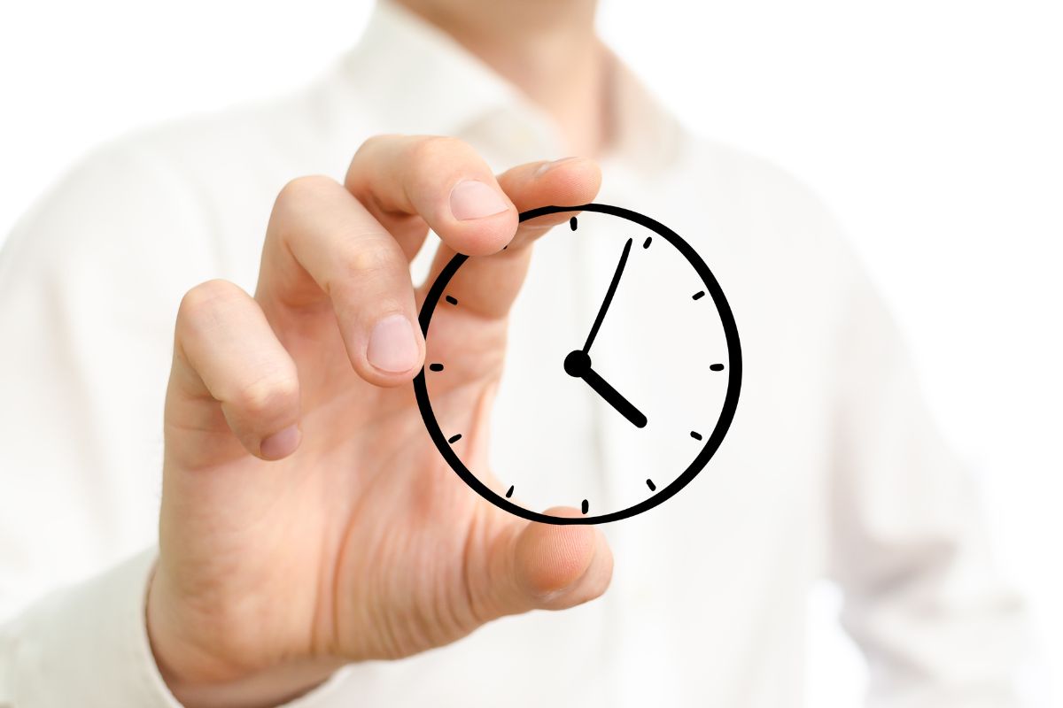 The image shows a man's hand holding a clock.