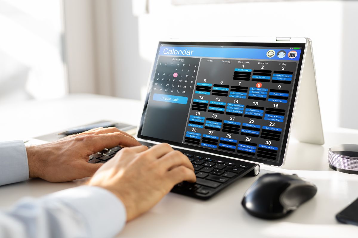 The image shows a man's hand using a laptop referring to schedule money-making sprints that lead to better efficiency and stronger financial results.
