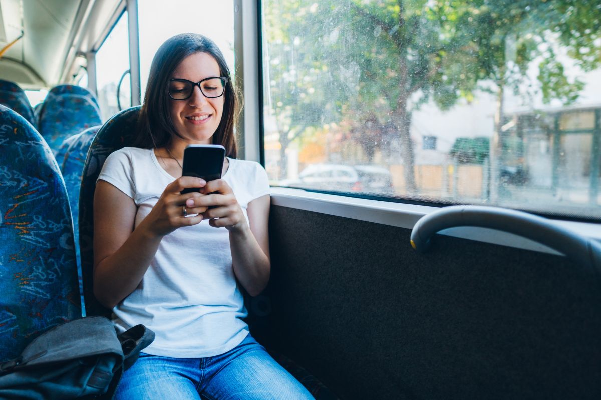 The picture shows a girl sitting on the bus while using a phone which refers to optimizing waiting time while commuting helping to stay on top of work and bring in more income.