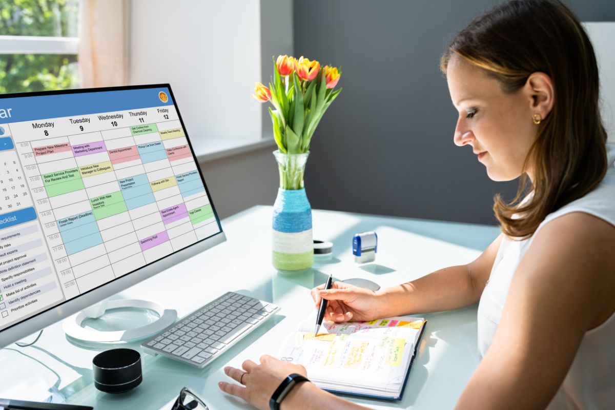 The image of a flower vase, a stamp, a computer with a screen display, and a girl checking the notebook which refers to the practice of aggressive calendar blocking keeps time focused on money-making activities.