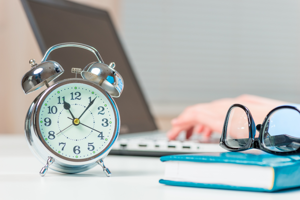 The picture tells about a notebook, an eyeglass, a clock, and a girl's hand using a laptop indicating that designated income hours task make a significant impact on overall income.