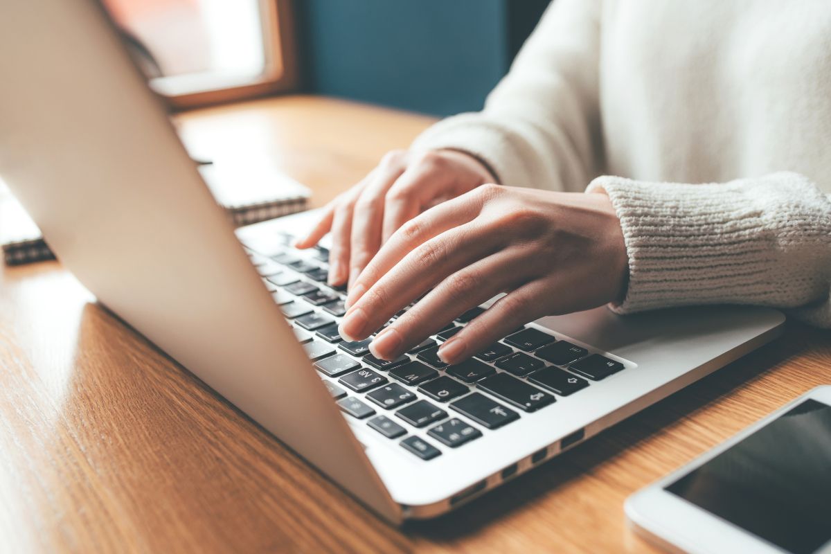 The image shows a phone, a notebook, and a girl's hand using a laptop which refers to the use of the double-down method saves time on trial and error while maximizing earnings.