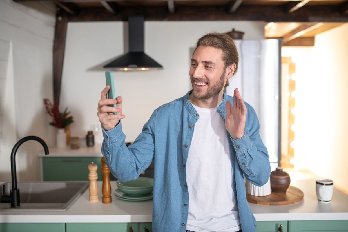 The picture of a man filming himself in the kitchen which refers to personalize video messages for niche audiences is a fun way to earn money without needing a full-time commitment.