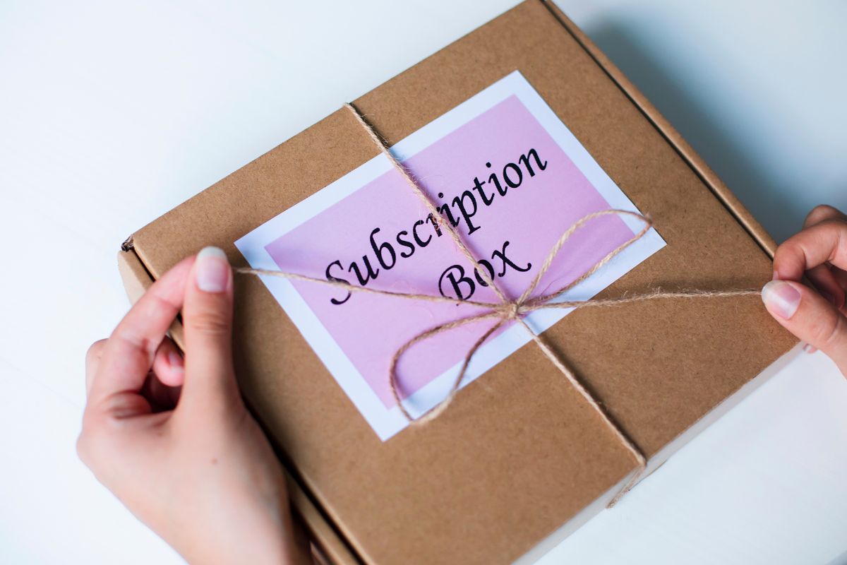 The picture shows a box with notes and a girl's hand unwrapping the tie which refers to niche subscription box curation that can grow into a steady online business with repeat customers.