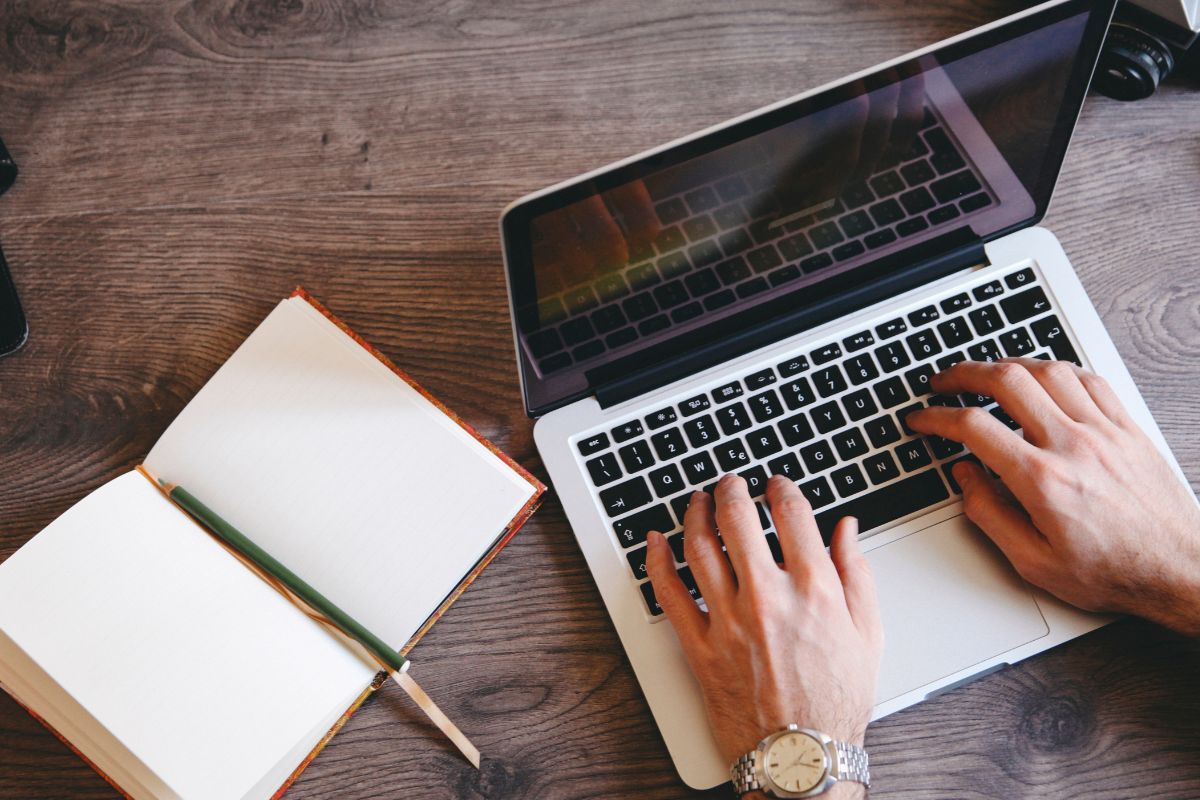 The image is about a man's hand working on ghostwriting.