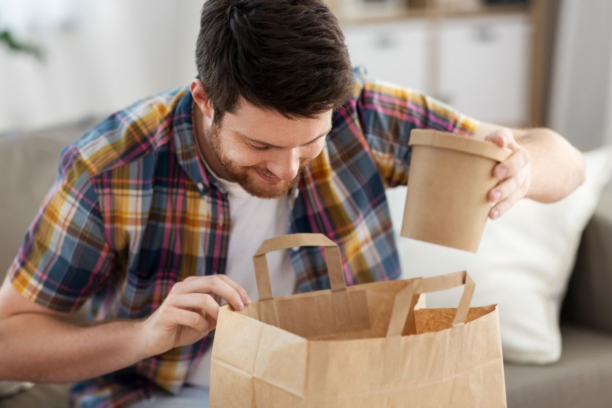 The image shows a man with take-out food.