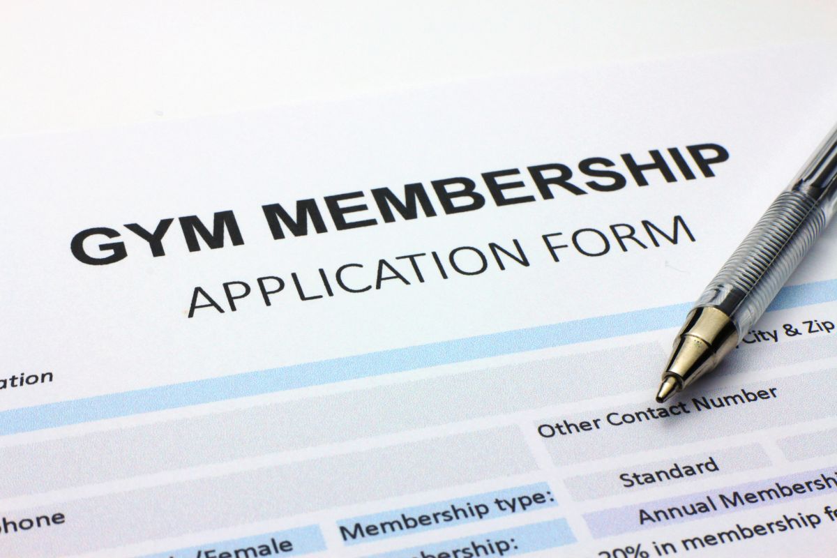 The photo tells about a pen and a piece of paper with notes indicating that unused gym memberships get wasted each month, home workouts, and free exercise apps are good alternatives.