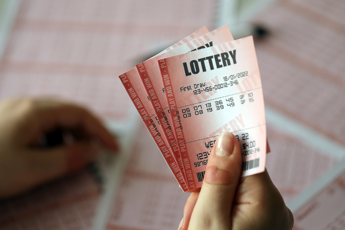 The picture shows a lady's hand holding lottery tickets.