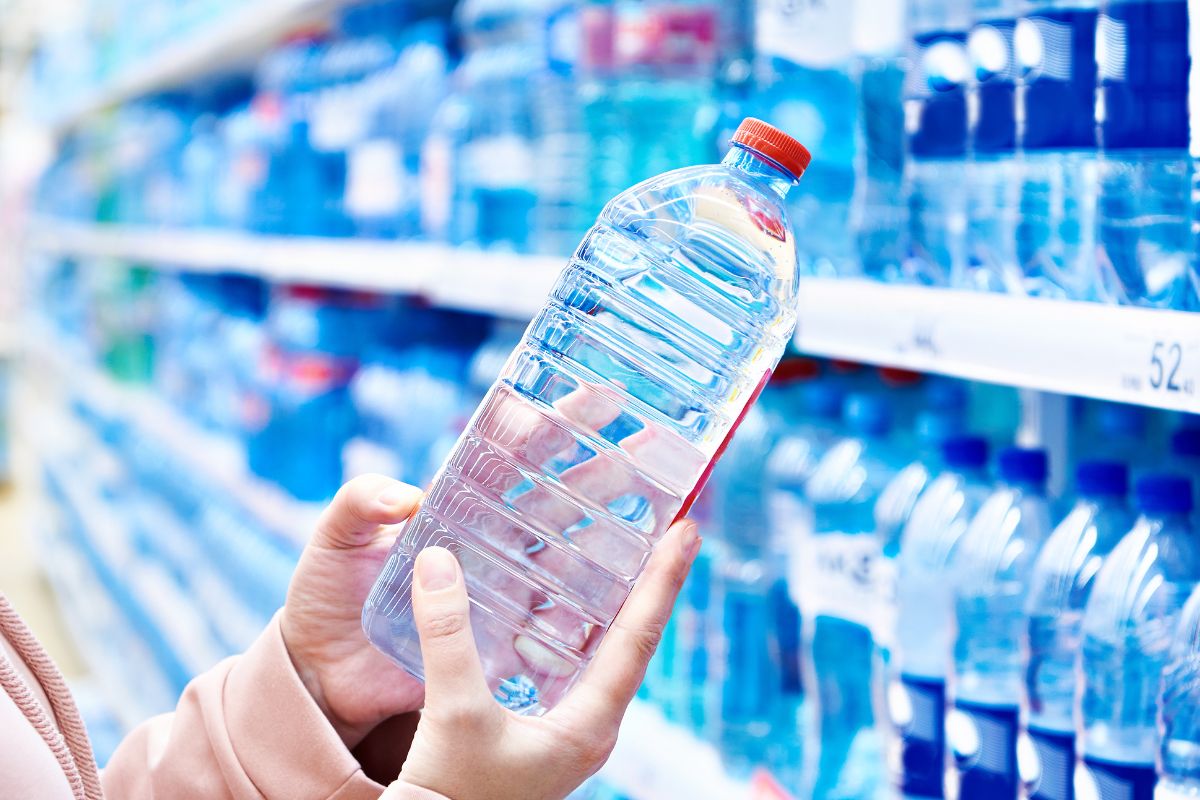 The image shows a lady's hand holding a bottle of water.