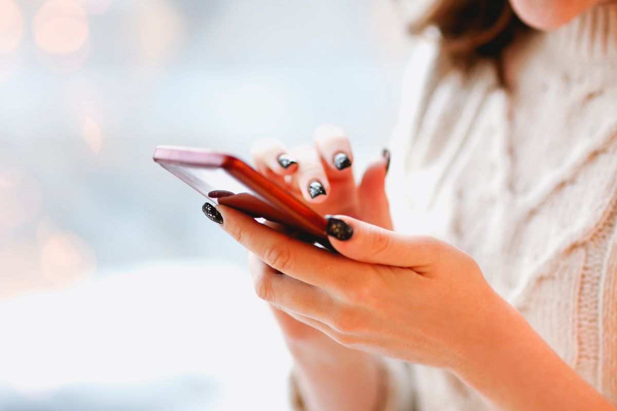 The picture tells about a girl's hand using a phone referring to upgrading phone plans as wasted money, cutting back on extras or add-ons can also save cash.