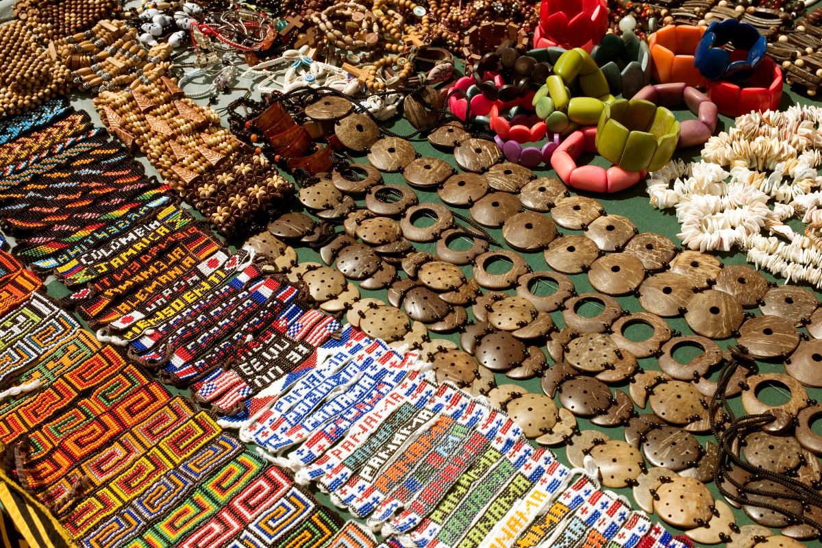 The image tells about different kinds of bracelets and lards on the table indicating that overpriced tourist souvenirs end up forgotten in a drawer, skipping buying them can save that money for something more practical.