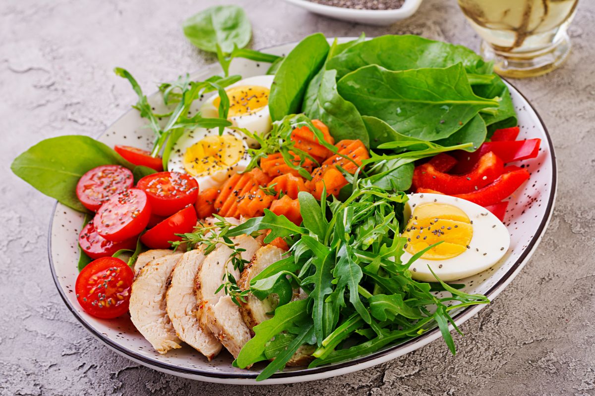 The picture shows a bowl full of meats, vegetables, and eggs which refers to trendy diet foods worth the high prices, sticking to whole foods can be healthier and save money.