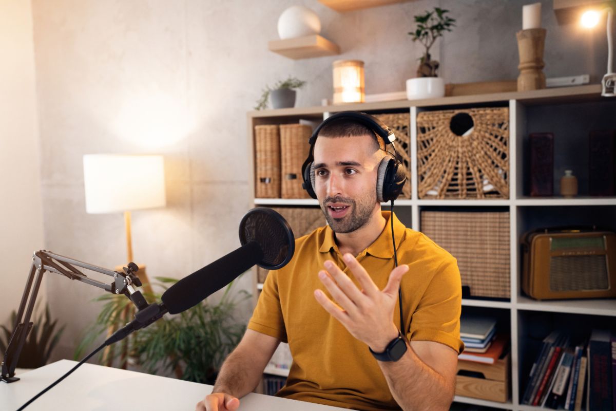 The picture tells about a man speaking while recording on a microphone with a headphone which means podcasting with sponsorship and ads is a creative way to make money from anywhere with just a microphone and internet.