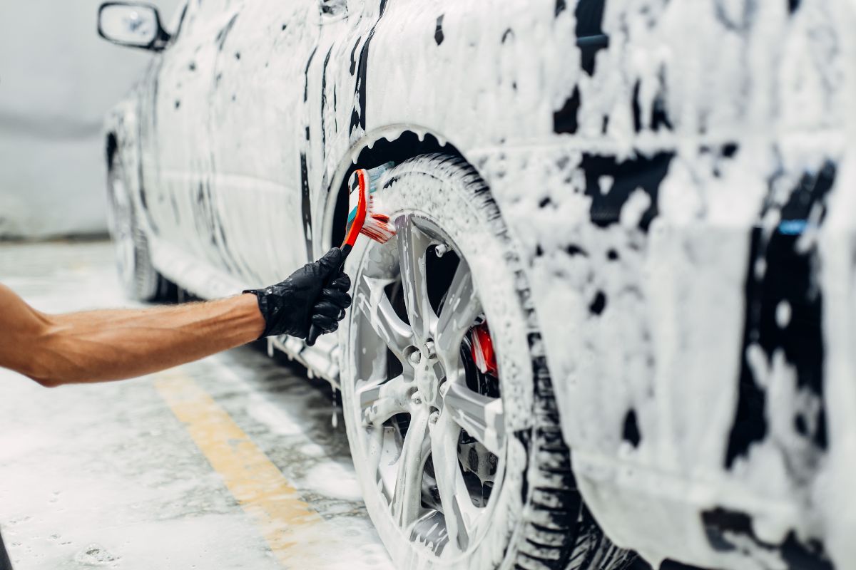 The picture shows a man washing a car.