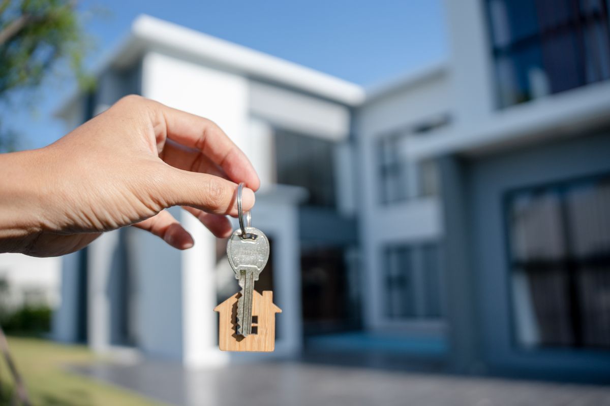 The image shows a man's hand buying an expensive house.