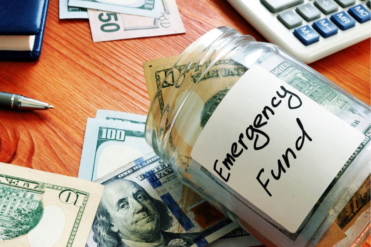 The image shows a jar filled with money for an emergency fund.