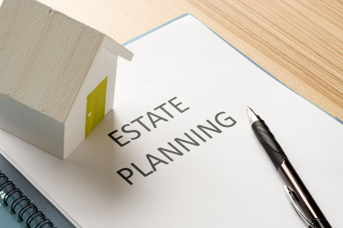 The picture shows a pen, a mini house, and a notebook with notes indicating that procrastinating on estate planning can cause problems, a clear plan protects wealth and loved ones.