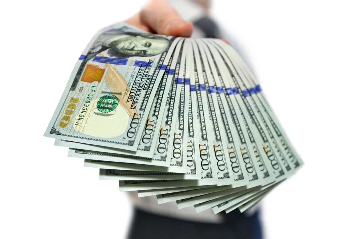 The image shows a man's hand holding dollar bills which means  time to become financially independent by making smarter choices that can lead to big financia wins.