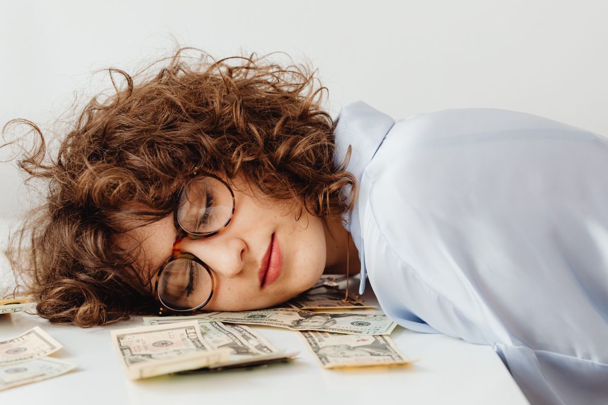 The image tells about a girl sleeping with dollar bills on the table referring to if you don't find a way to make money while you sleep, you'll work until you die which you need to build income streams that don't require your time.