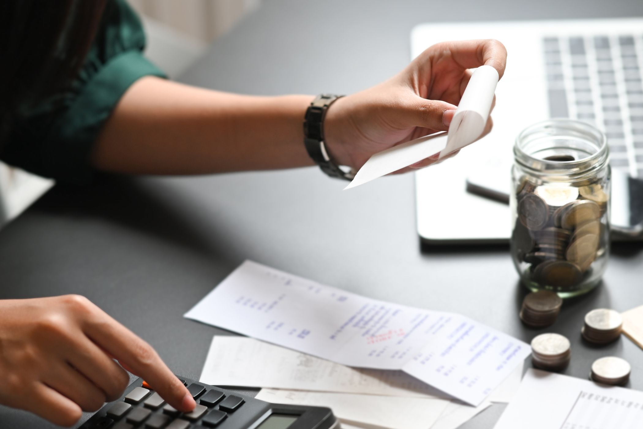 The image shows a woman's hand calculating expenses.