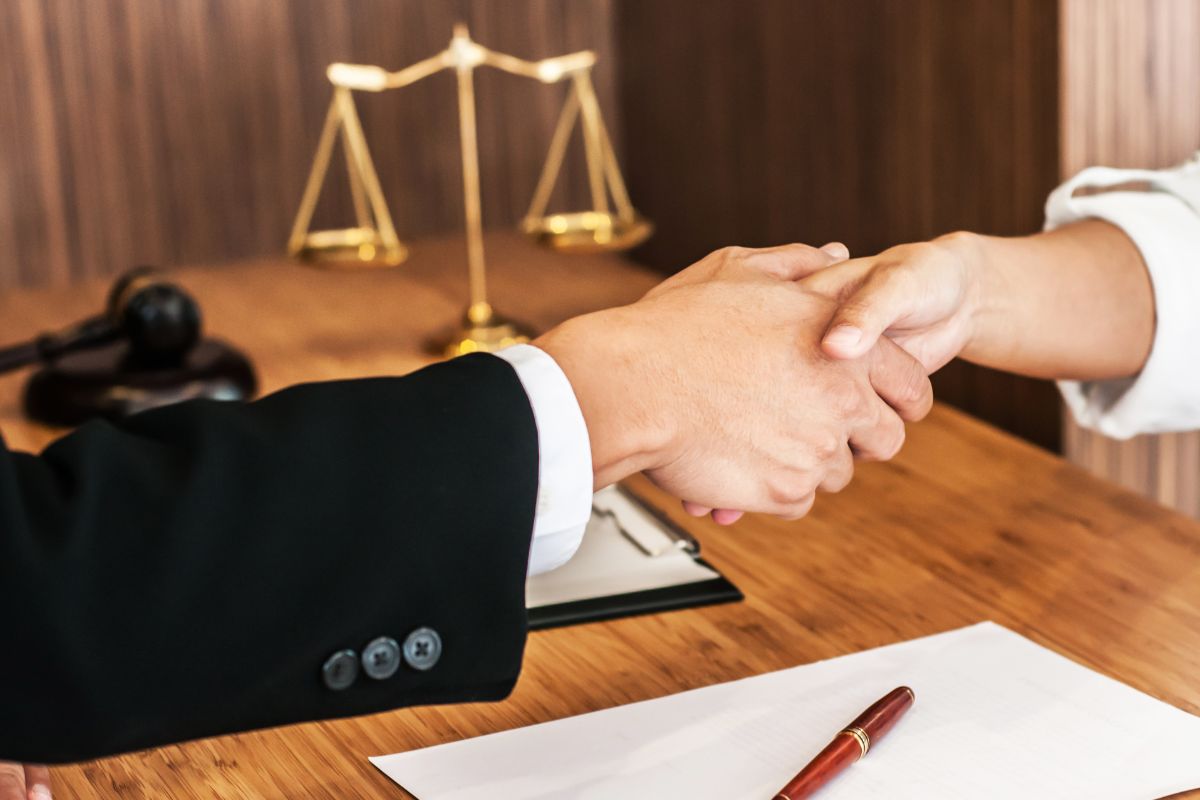 The image shows corporate lawyers handshaking.