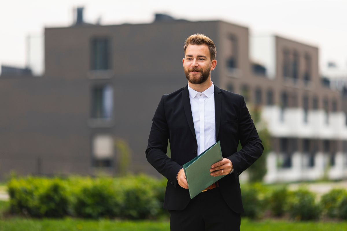 The picture shows a man holding documents which refers to a luxury real estate agent who sells high-end homes is great with people and wants a career in sales.