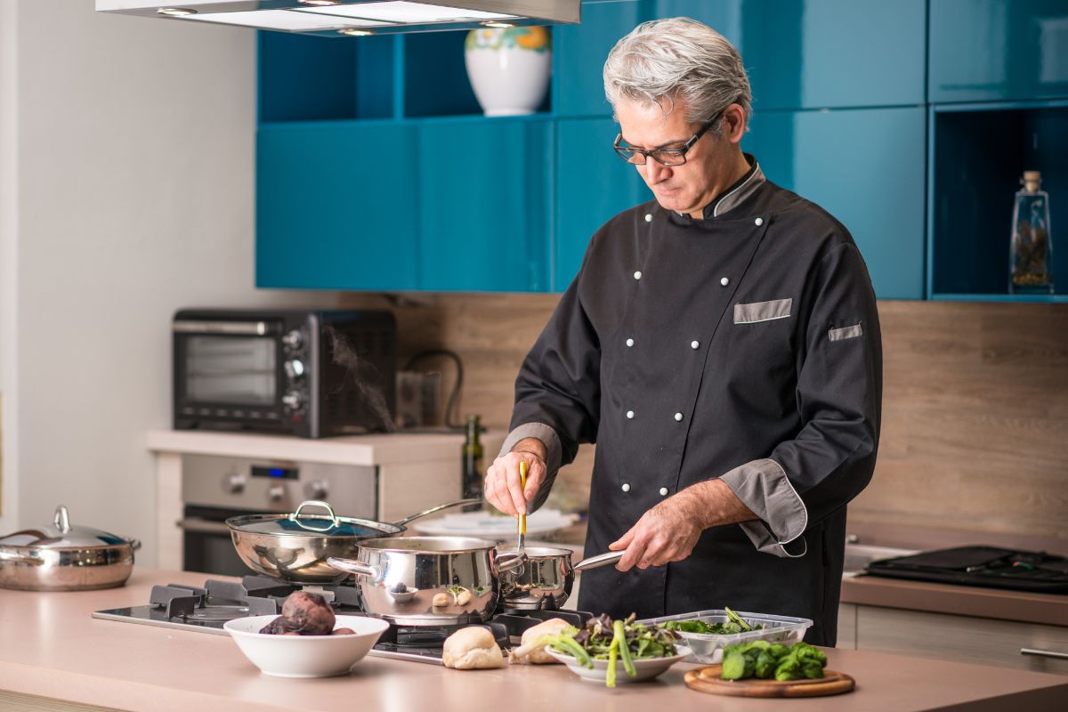 The image tells about kitchen utensils and a chef preparing food referring to a private chef for celebrities a job that pays well with high-profile clients demanding top-quality food and service.