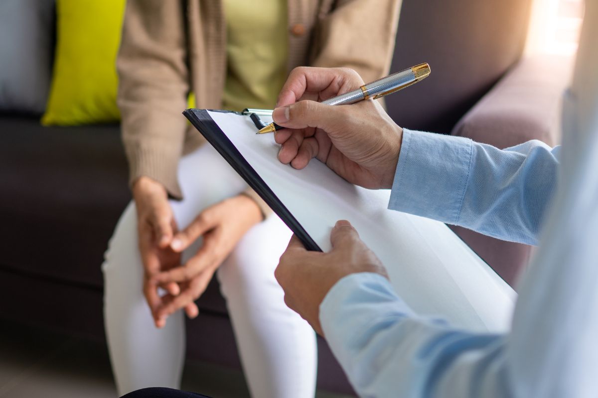 The photo shows a man writing on the paper and a girl sitting on a couch indicating that genetic counselors help people understand their genetic risk for disease is in high demand that pas well.