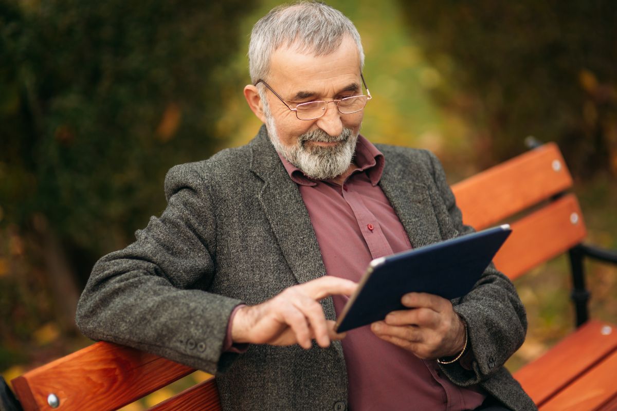 The photo tells about an old man using a tablet device which refers to a standard retirement age is a good choice for those who want financial stability while still having time for personal interest.