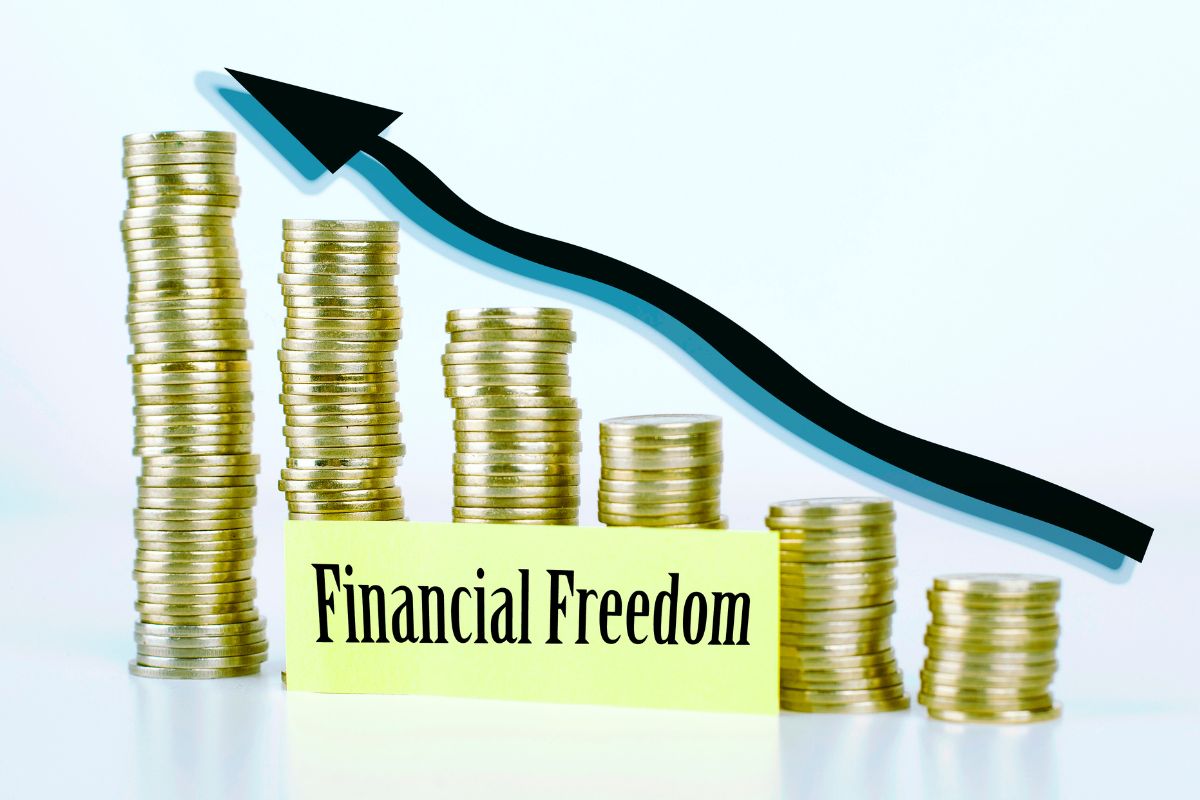 The image shows stock coins, an arrow, and a piece of paper with notes which refers to time to work through the money bliss steps to financial freedom that can help make retirement enjoyable and stress-free.