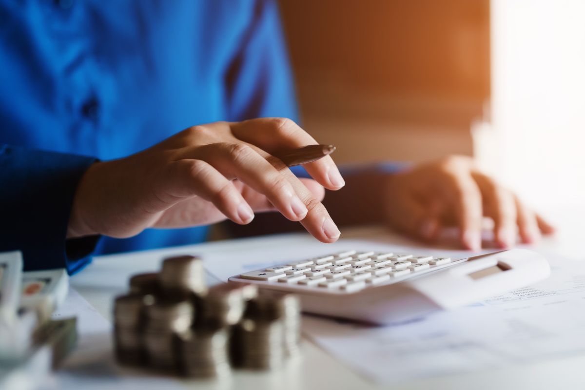 The photo tells about coin stock, dollar bills, papers, and a man's hand calculating which refers to value-based budgeting helps avoid wasting money on things that don't bring value.
