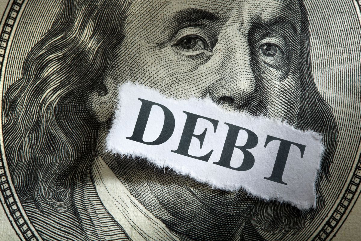 The photo tells about a dollar icon and a piece of paper with a note which refers to debt snowball vs. debt avalanche helps pay off debt fast.