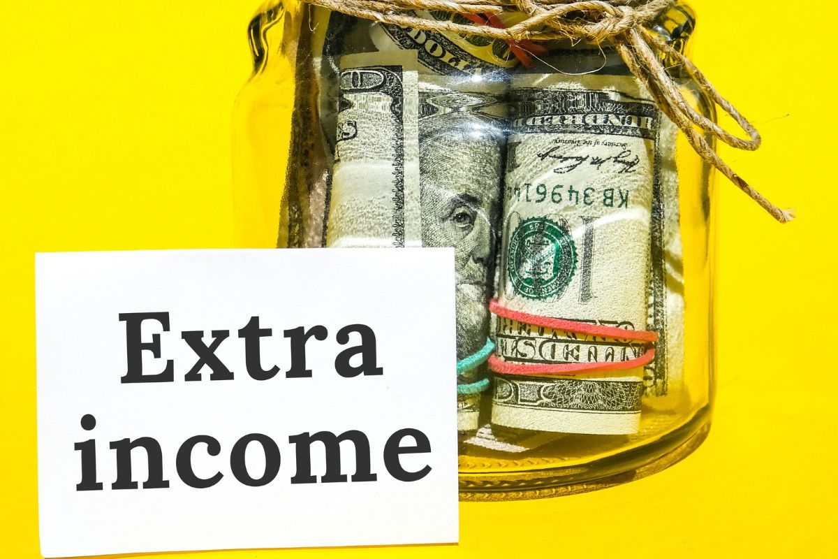 The image tells about a jar filled with dollar bills and a piece of paper with notes indicating to side hustle income allocation makes financial progress faster.
