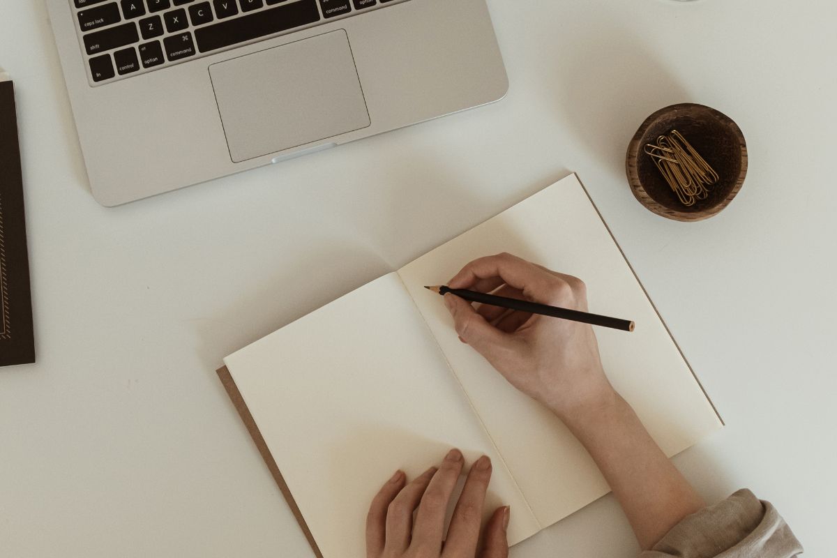 The image is about a woman's hand and writing in a notebook.