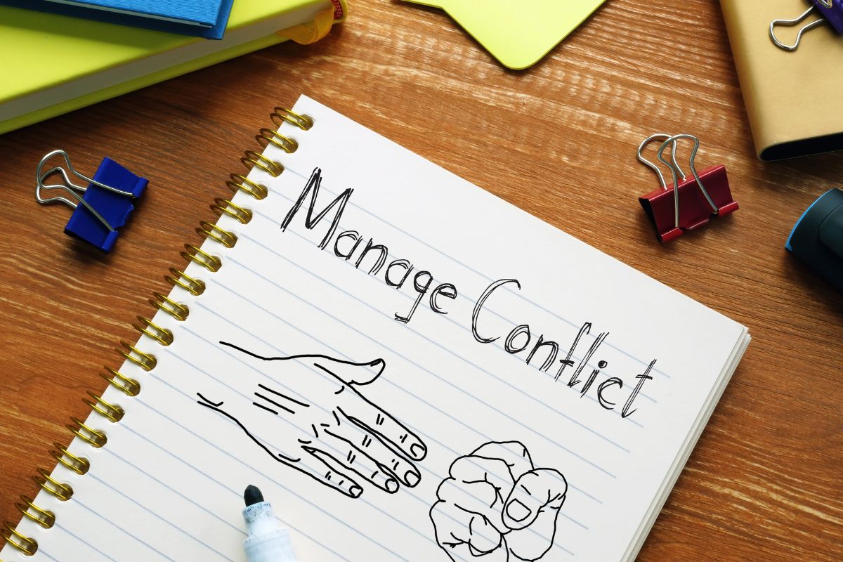 The photo shows a notebook with a management conflict note. 