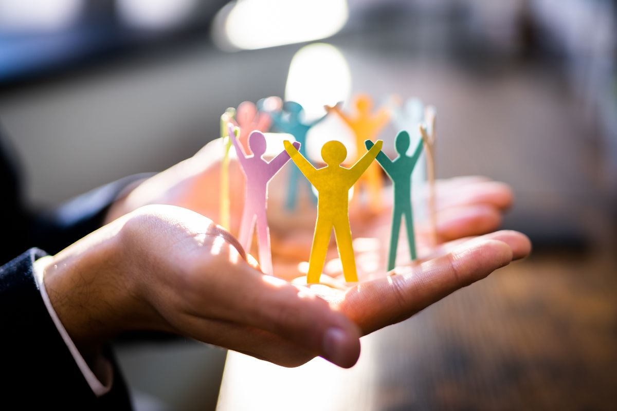 The picture tells about a girl's hand holding human figure paper which means learning leadership and teamwork early makes career growth smoother.