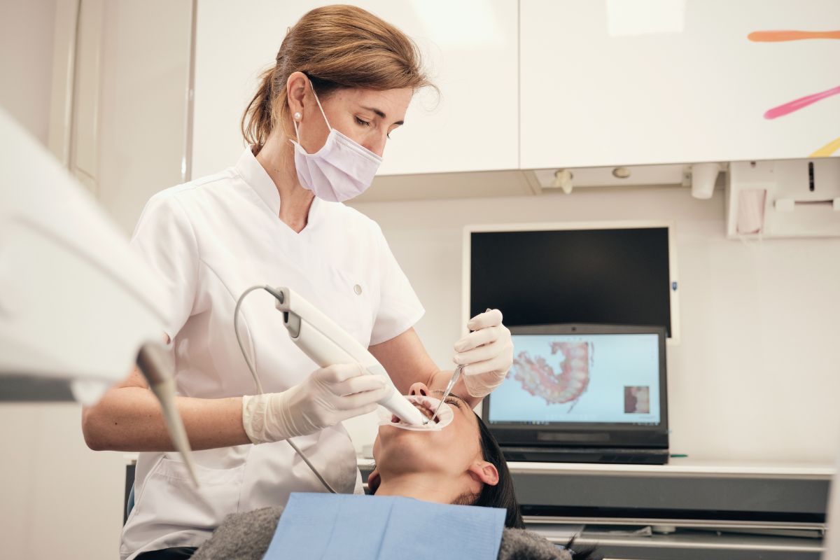 The image tells about a dentist cleaning her patient's teeth indicating that an orthodontist helps people get straight teeth and a better smile which pays well and is one of the profitable careers.