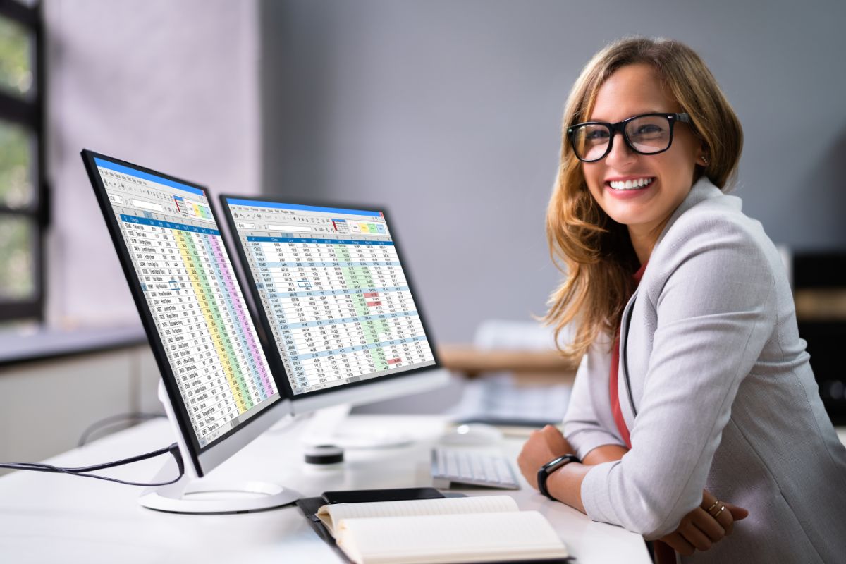 The photo shows a computer set, a notebook, and a girl in a white suit smiling which means a data scientist helps businesses make better decisions that are in high demand and can make you a lot of money.