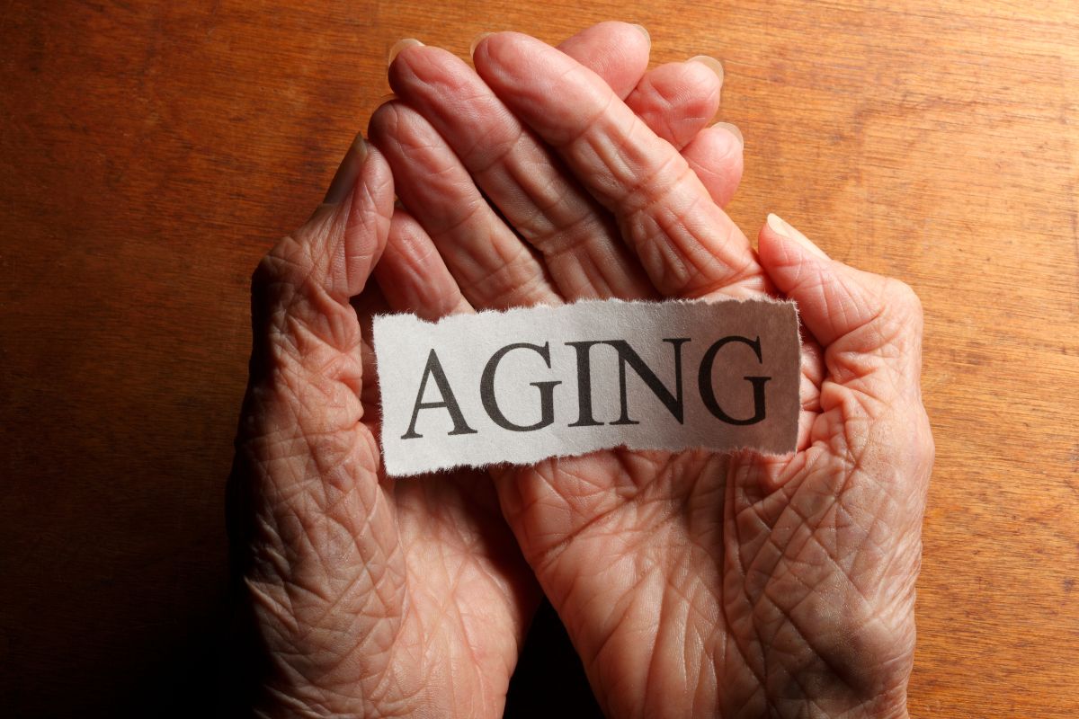 The photo shows a senior hand holding a piece of paper with a note indicating to closer to retirement age and having no savings is not a hindrance, taking action now can improve your situation.