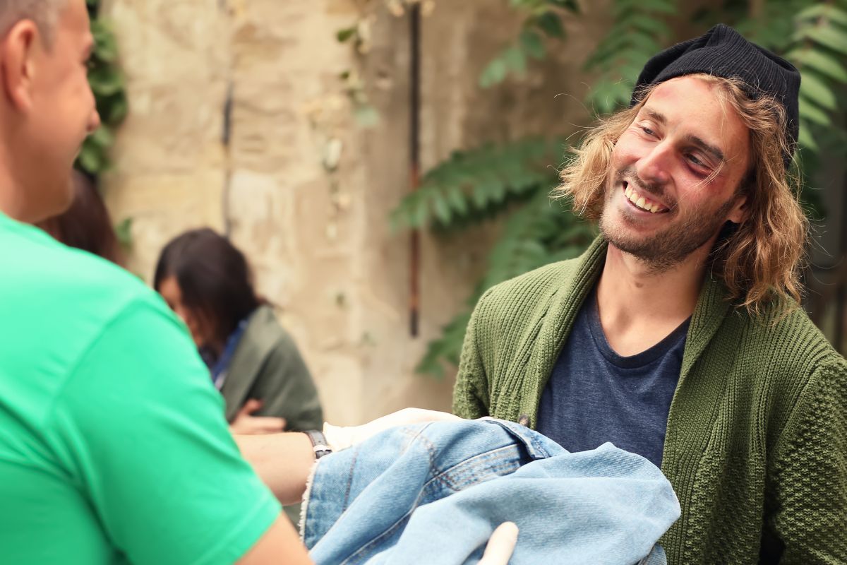 The photo tells about a man giving clothes to the man.