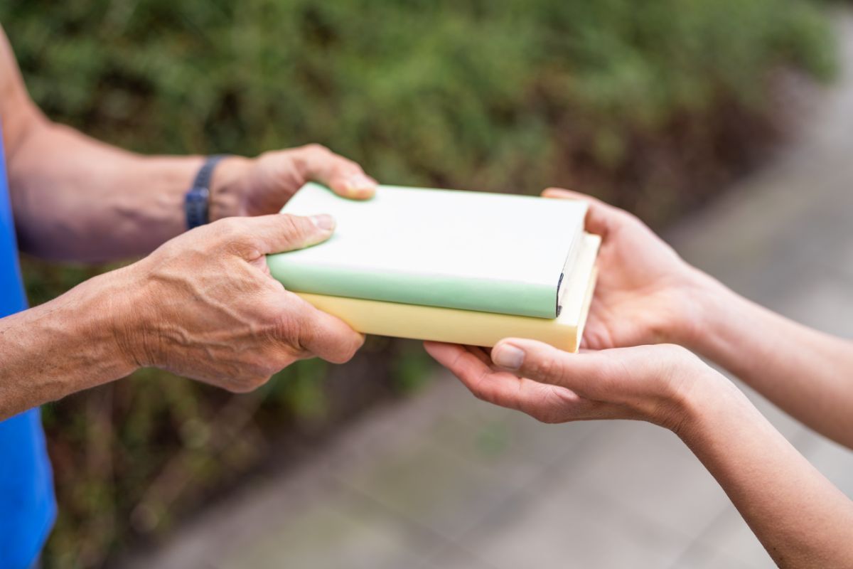 The photo tells about a senior's hand handing books to the girl's hand which refers to borrowing instead of buying helps avoid cluttering up the house with rarely used items.