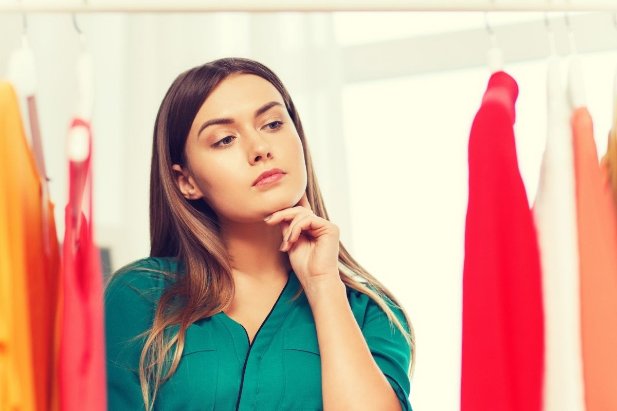 A young women thinking while looking at the clothes. 