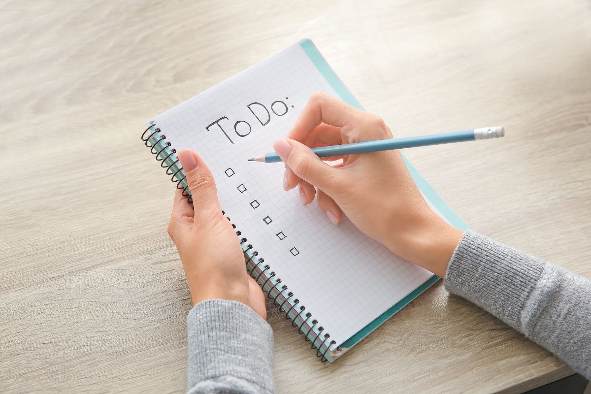 The image tells about a girl's hand and writing on the notebook indicating to start a free entertainment list makes it easier to enjoy life without blowing the budget.