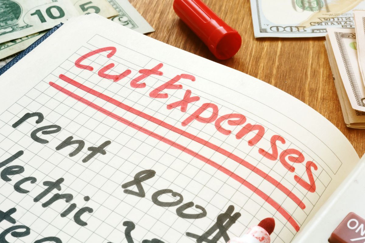 Picture of a notebook with cut expenses wording. 