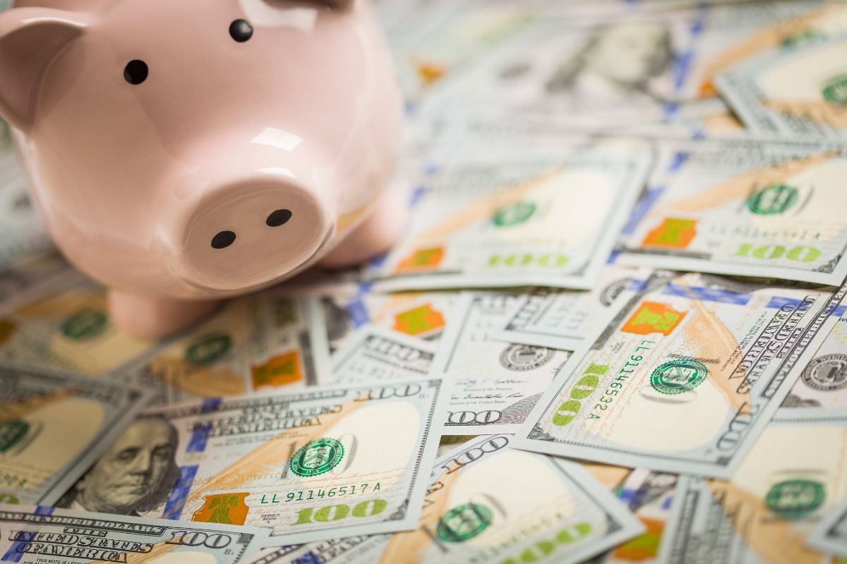 The image shows dollar bills and a piggy bank which means trying the most popular $10k challenge gives you a solid financial foundation for emergencies, investments, or big purchases without relying on debt.