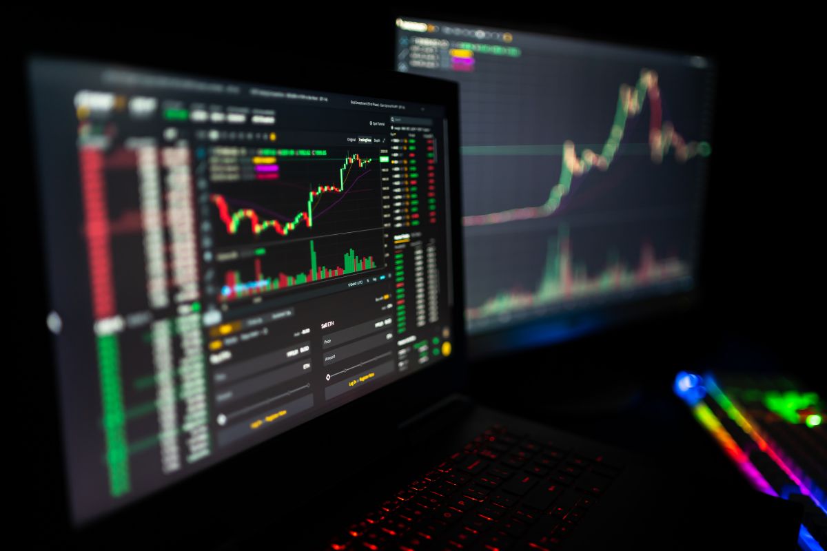 The image shows laptops with screen displays which means becoming a day trader could be a way to earn serious money.