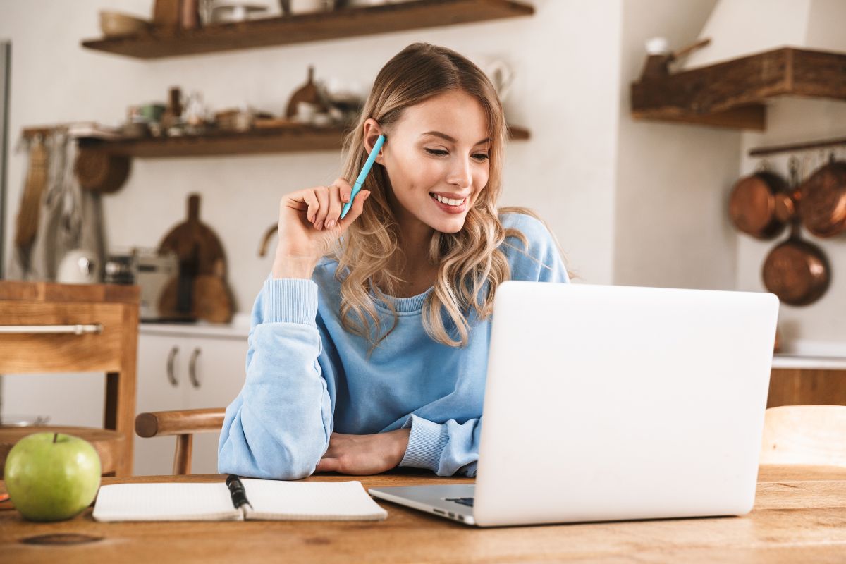 The picture shows an apple, a notebook, and a girl looking at a laptop referring to selling products on Etsy is hot right now that can provide passive income if you sell digital downloads.