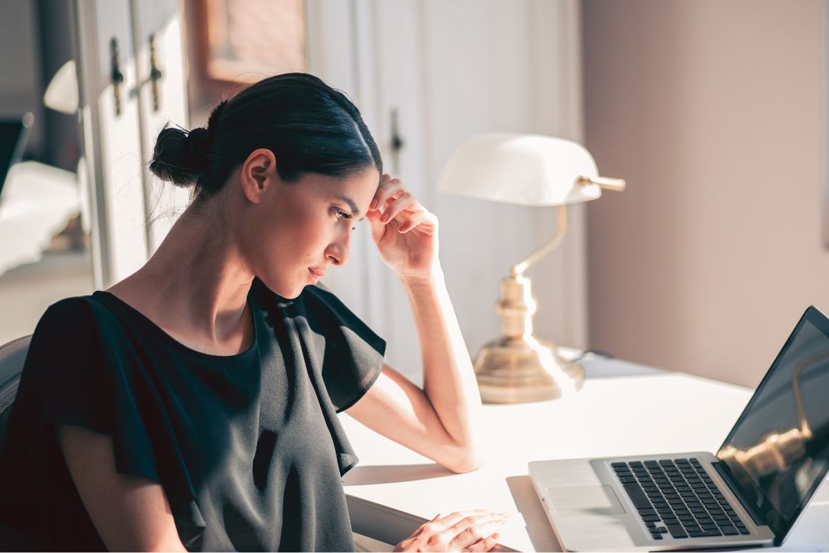 The image tells about a lamp and a girl looking at her laptop while thinking which refers to uncovering what you should do to find a side hustle that makes sense for your life and financial goals.