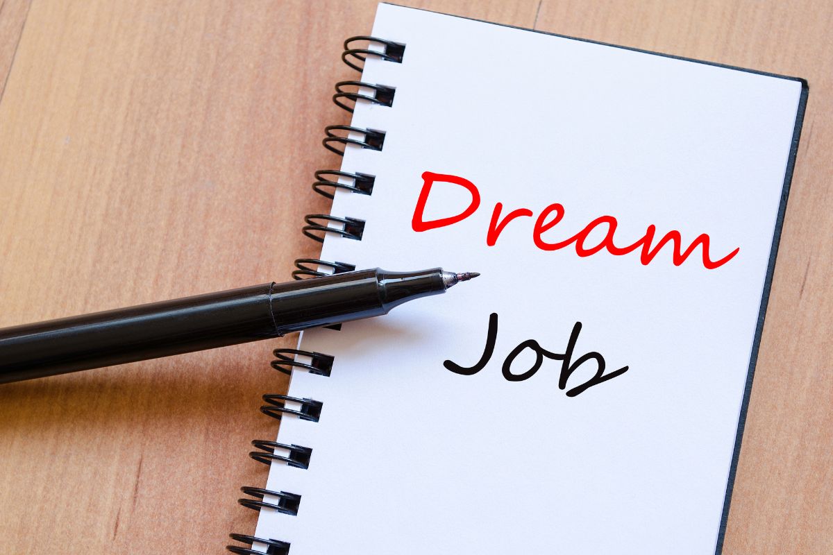 The picture shows a pen and a notebook with notes referring to manifesting your dream job that can open doors to better career opportunities.